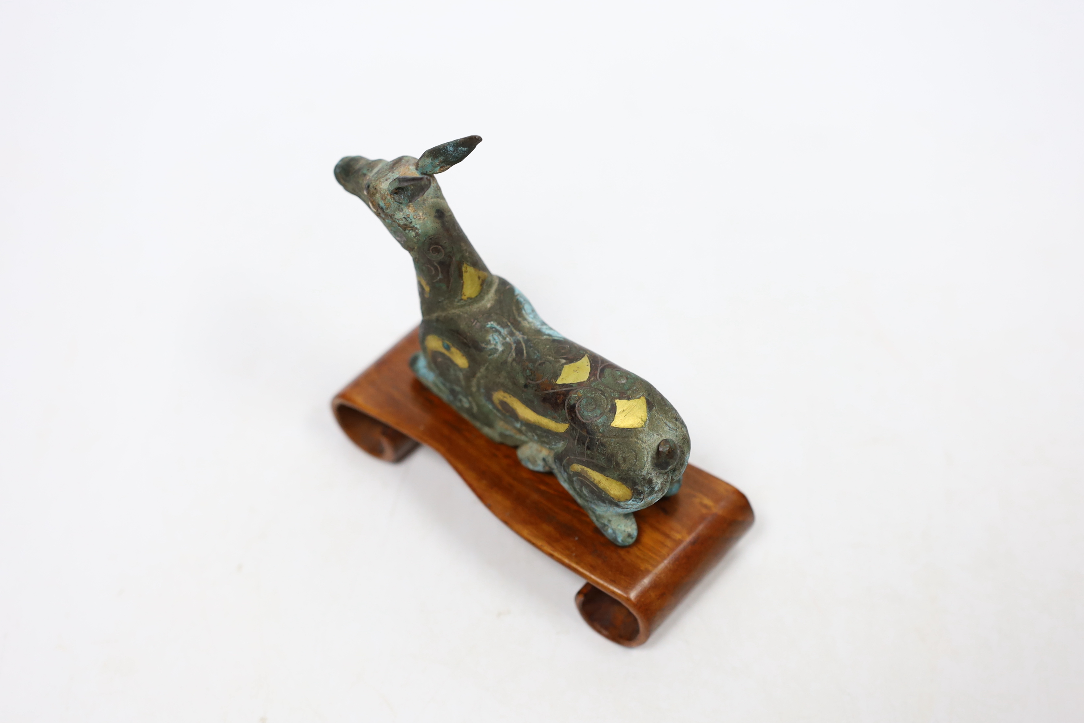 A Chinese bronze and parcel gilt Han style figure of a seated deer, and a small Etruscan terracotta head on stand